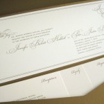 A classy, traditional, custom gold and ivory wedding invitation set with inserts and reply postcard.